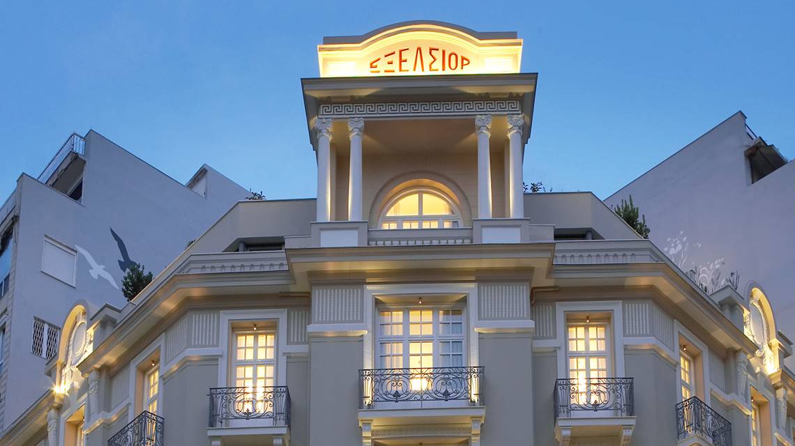 Illuminated facade of The Excelsior Hotel with balconies and neoclassical architecture at dusk