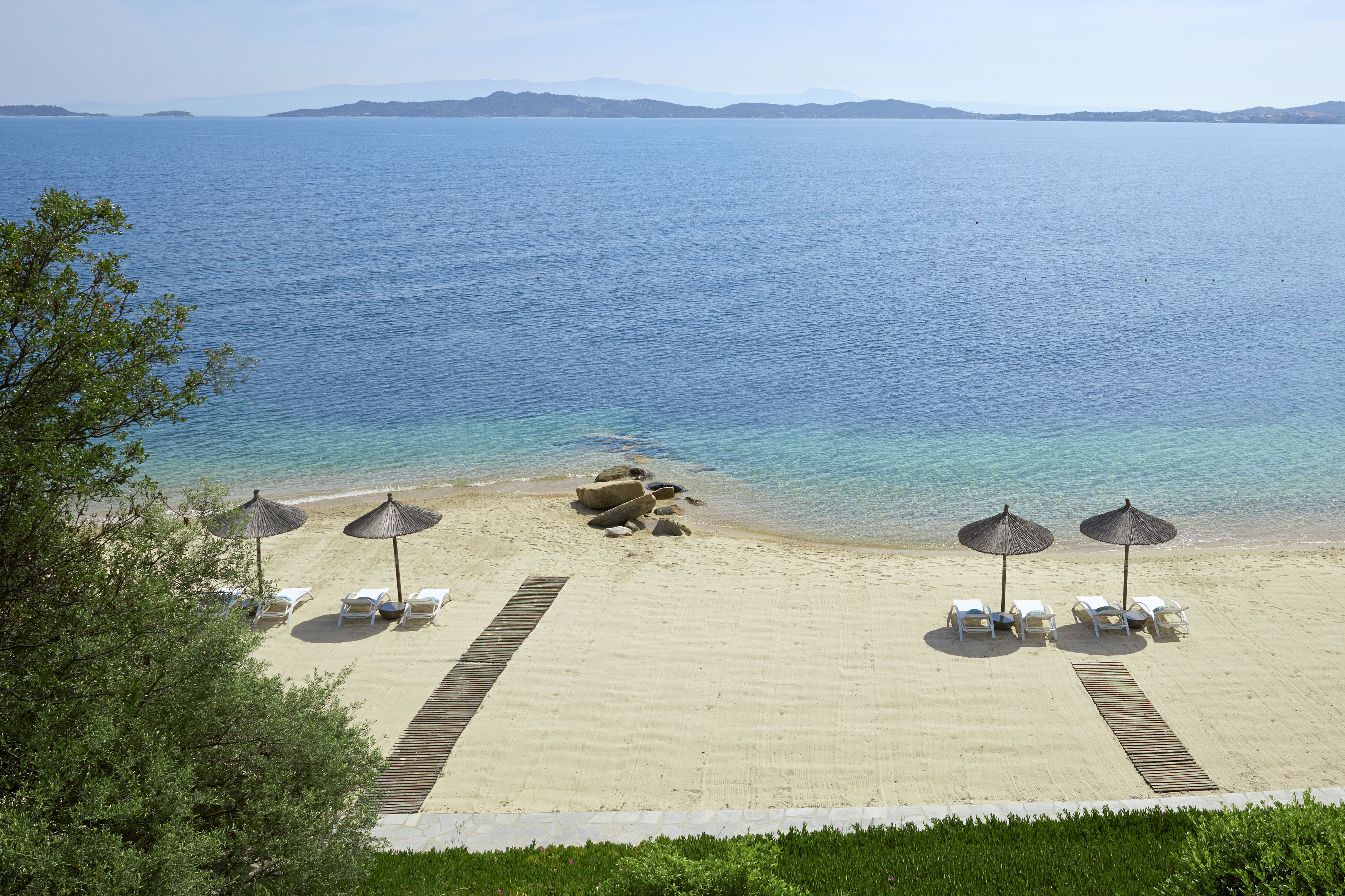 
Wide view of sandy beach sea shore at dusk with umbrellas and sun loungers at Eagles Resorts