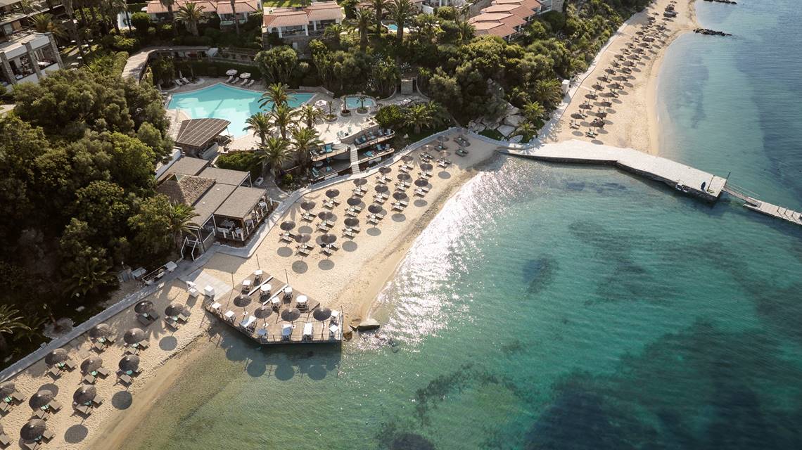 Aerial view of Eagles Resort, sandy beach with trees and umbrellas, and swimming pool