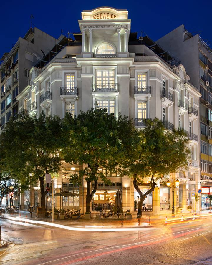 The Excelsior Hotel illuminated at night with neoclassical facade, balconies and street cafe